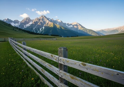 Scenic mountain landscape with wooden fence and green meadow under clear sky - Powered by Adobe
