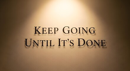 A motivational quote displayed on a wall with warm lighting that encourages perseverance and determination to complete tasks and achieve goals