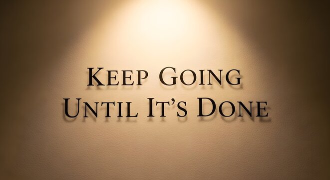 A motivational quote displayed on a wall with warm lighting that encourages perseverance and determination to complete tasks and achieve goals