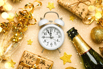 Top view of white alarm clock with bottle of champagne,crystal glasses,golden christmas balls and...