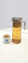 glass teapot with hot tea and traditional porcelain teacup, minimalist tea ceremony setup, steaming glass teapot with ceramic teacup on marble table, minimalist teapot features a metal lid and handle 