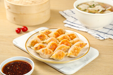 Traditional Handmade Steamed Dumplings with Dipping Sauce and Bamboo Steamer on Wooden Table