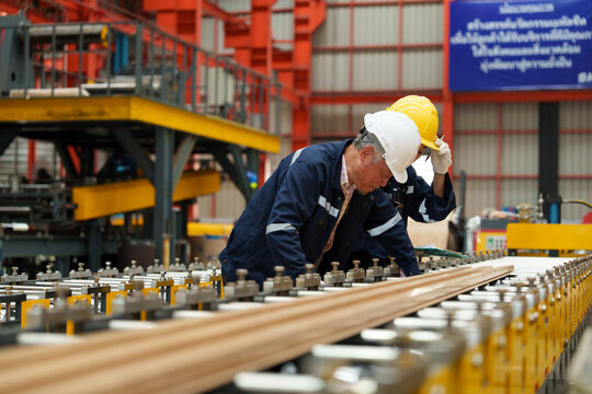 Engineers and staff inspect the production line of components in a metal sheet and metal roofing manufacturing plant. - Powered by Adobe