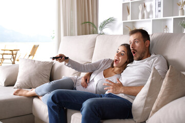 Amazed couple watching surprising tv program