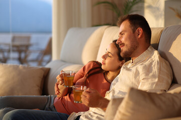 Happy couple in love at sunset drinking tea at home