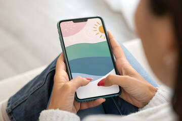 Close-up of woman holding smartphone with colorful abstract app screen indoors. Concept of digital creativity, technology, mobile design, and relaxation.