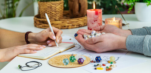 Numerology Divination consultation: woman writing in a notebook, man holding fortune stones.