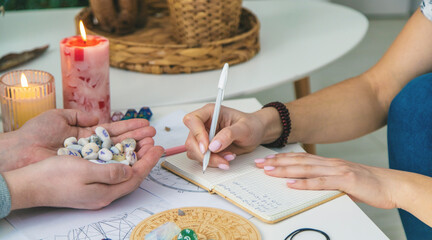 Numerology Divination consultation: woman writing in a notebook, man holding fortune stones.