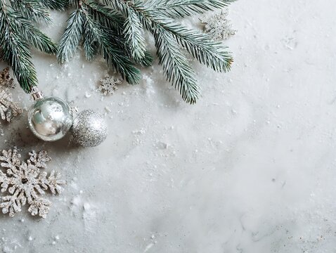 Top view of snow texture background with Christmas decor &mdash; pine branches, snowflakes, and silver ornaments.