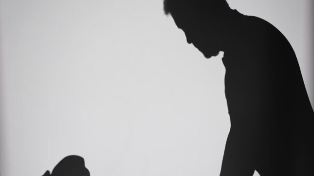 Silhouette of a man holding a golf putter, preparing for a stroke, cast sharply on a smooth light surface. Minimalist with ample copy space
