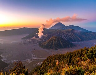 Aerial view of volcanic mountains with smoke emitting, against a backdrop of a colorful sunrise