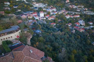 Fototapeta premium Aerial view of Kruja’s hillside homes and olive groves with stone terraces and traditional rooftops at dusk.