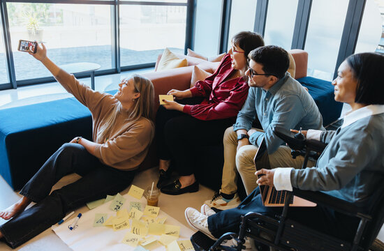 Group of professionals collaborating and taking selfie in modern office environment