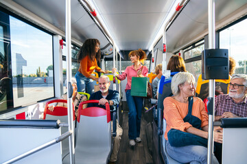 Diverse group of smiling people commuting and traveling inside a modern city bus enjoying public transport