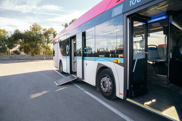 Modern electric city bus with an automatic wheelchair ramp deployed, highlighting accessibility for...