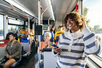 Young woman smiling, enjoying music with headphones and smartphone on a public city bus. People traveling to work
