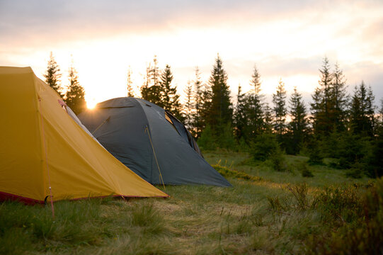 Two tents at sunrise in the morning on the hill. Two tents pitched on a hilltop, bathed in the soft, colorful light of the morning sun. Camping tent on the hill in the morning.