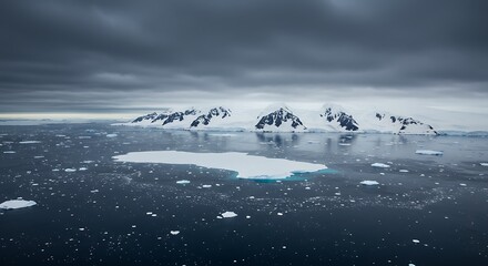 Aerial view of a glacial island with snow-capped mountains surrounded by ocean waters under dark clouds