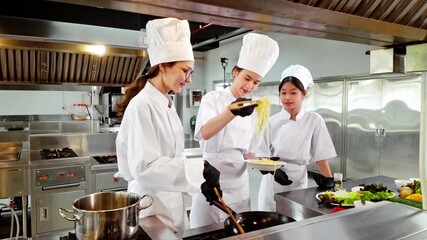 Chef instructor and two students tasting freshly cooked pasta in a commercial kitchen during a hands-on culinary training class. Perfect for promoting chef school, cooking education, and food skills. - Powered by Adobe