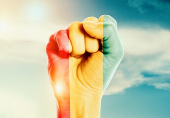 Guinea national flag fist raise in the sky. The hand with flag raise in beautiful soft sky. Guinea...
