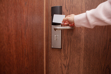 Young woman opens modern hotel room door with an electronic key card. Concept of travel, hospitality, safety, vacation, business trip, and contemporary hotel technology.