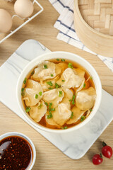 Handmade Gourmet Dumplings in Broth with Traditional Preparation Setup and Spicy Sauce
