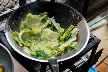 Vegetables steaming in a wok at a Thai street food kitchen