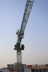 Green tower crane against blue sky
