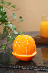Fresh Peeled Navel Orange Segments on Slate with Juice Glass and Plant Decor