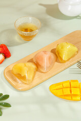 Heart-shaped crystal rice dumplings with fruit and tea - traditional Asian sweet dessert on wooden serving board