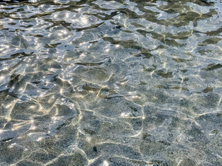 Clear Water Ripples Over Sandy Beach Bottom with Natural Light Patterns