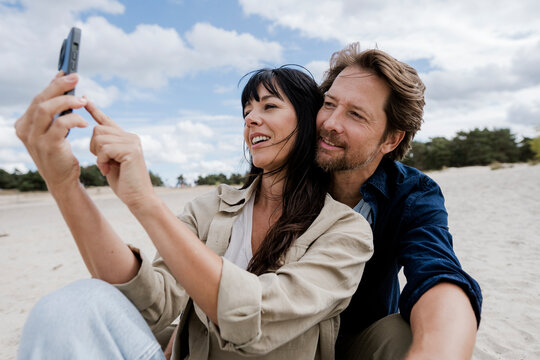 Couple taking a selfie together on a windy day at the beach