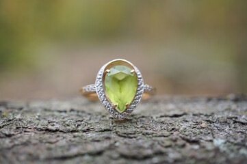 A precious ring with chrysolite on a wooden background.