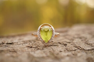 A precious ring with chrysolite on a wooden background.