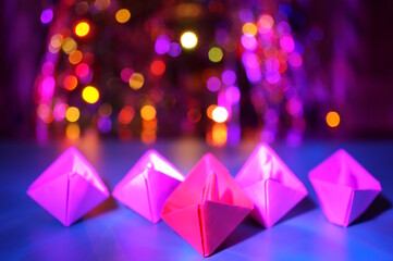 A group of paper boats on the background of a Christmas garland.