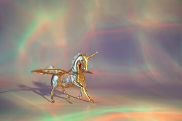 A unicorn figurine on a pink rainbow background.