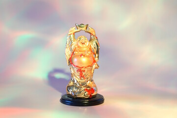 A statue of a smiling Buddha on a pink rainbow background.