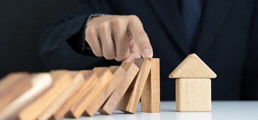 insurance with hands protect house. Businessman hands stop dominoes falling in house crisis. business risk control and planning and strategies to run prevent insurance businesses.