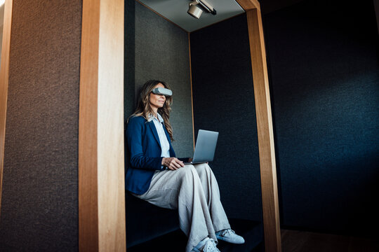 Businesswoman using VR glasses with laptop in a modern quiet zone