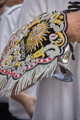 Close-up of an ornate embroidered banner with gold, silver, and red threads during the Virgen del Rosario procession in Granada. Faith, tradition.
