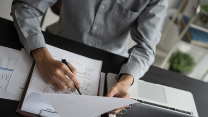 Asian business man holding paper document calculating tax insurance managing budget