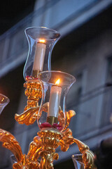 Detail of lit candles in glass holders with golden bases during a religious procession in Granada. Soft light and ornate design. ceremony, devotion