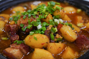 braised pork belly with potatoes being stewed in an iron pot