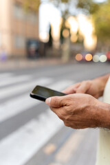 Person holding smartphone, typing message on urban street, navigating city
