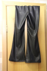 leather pants hang on a wooden door,