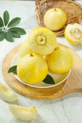 Sweet Fragrant Yellow Melons with Star Pattern Core on Marble Table with Wicker Basket and Green Leaves