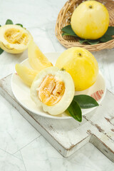 Sweet Linyi Star Melons Sliced Fresh on Rustic White Wooden Table with Wicker Basket