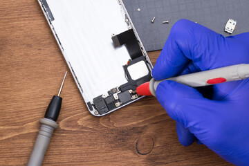 Using a voltage measuring device when repairing a phone display, close-up