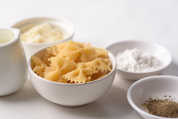 Farfalle pasta with cheese and black pepper, ingredients for Italian cooking on white background