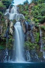 Tall Tropical Waterfall Cascading Down Rocky Cliff in Lush Jungle © SzymczakRadekPhoto